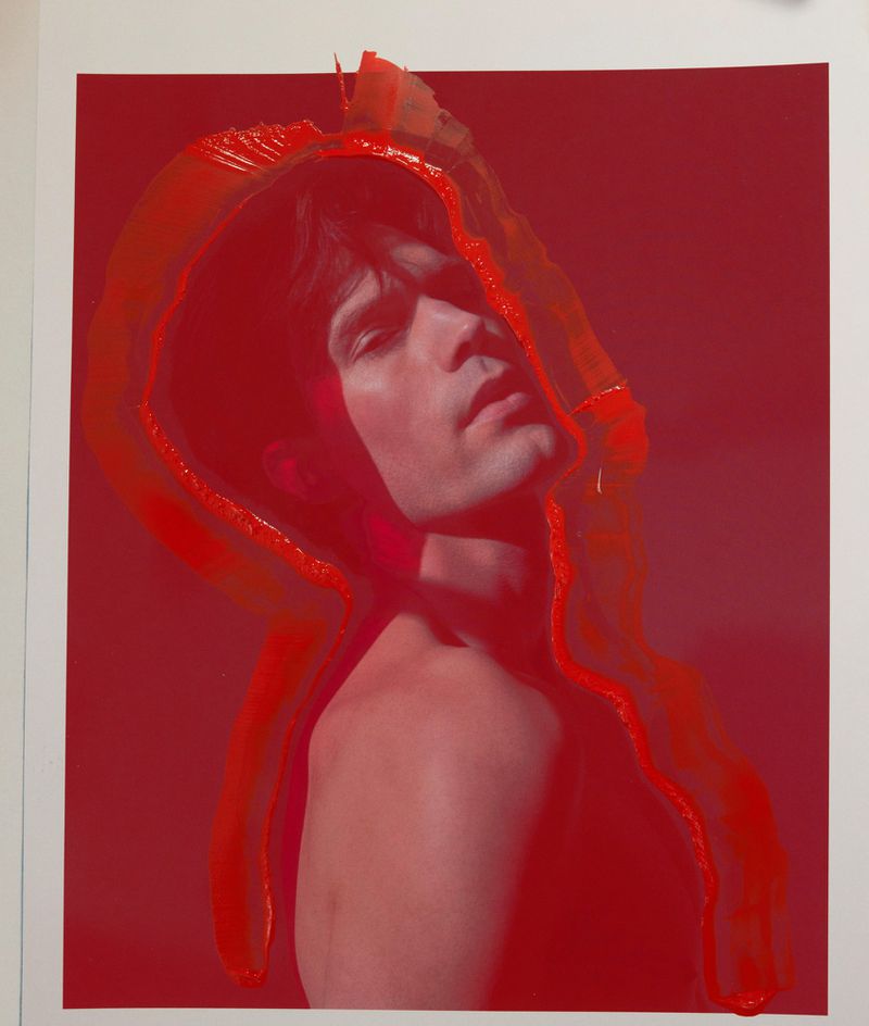 Artistic portrait of a shirtless man with head tilted back, framed by an overlay of red paint on a crimson background.
