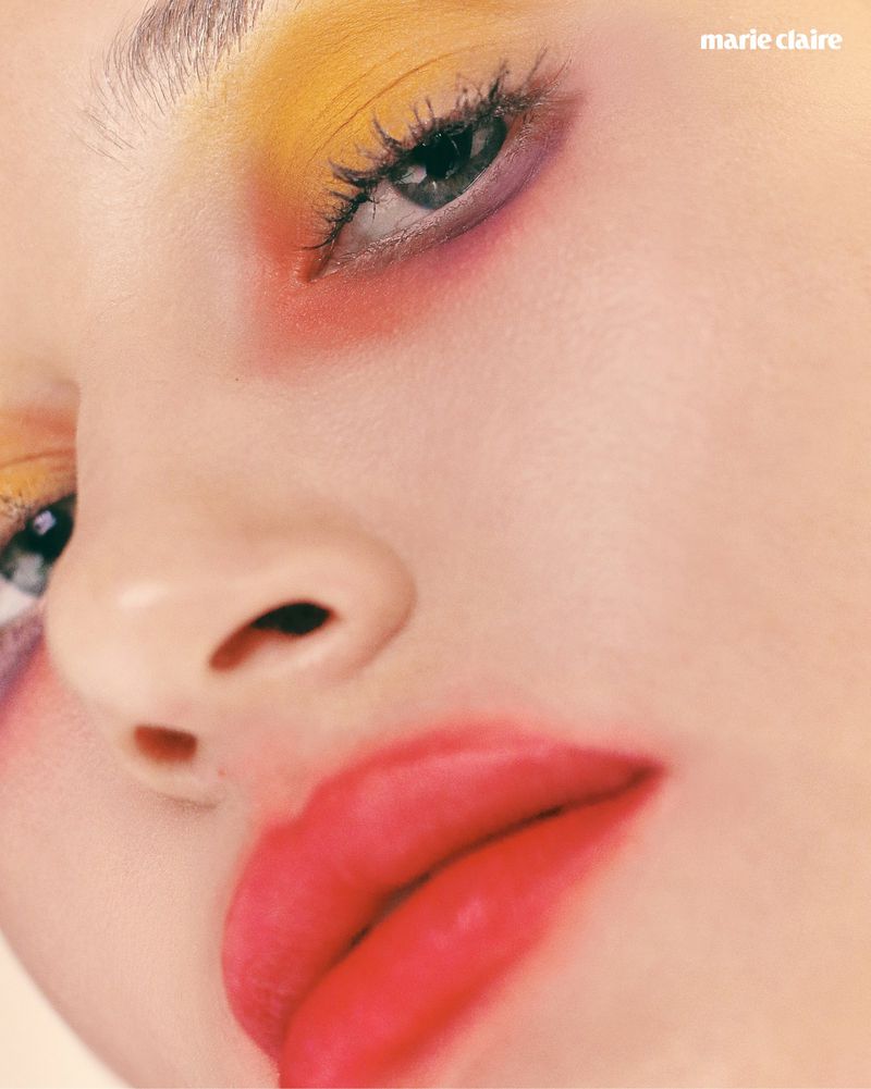 Extreme close-up beauty shot of a model with yellow and purple eyeshadow and diffused stained red lips.