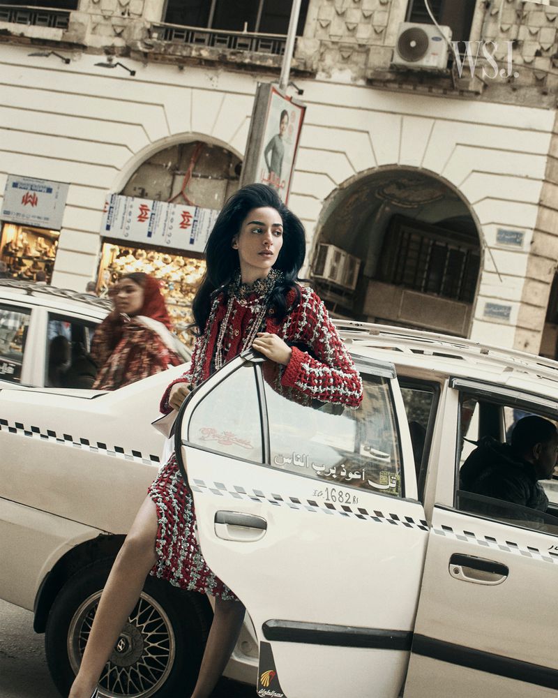Model Nora Attal stepping out of a vintage taxi in downtown Cairo wearing a red patterned coat for WSJ, photographed by Nikolai von Bismarck.