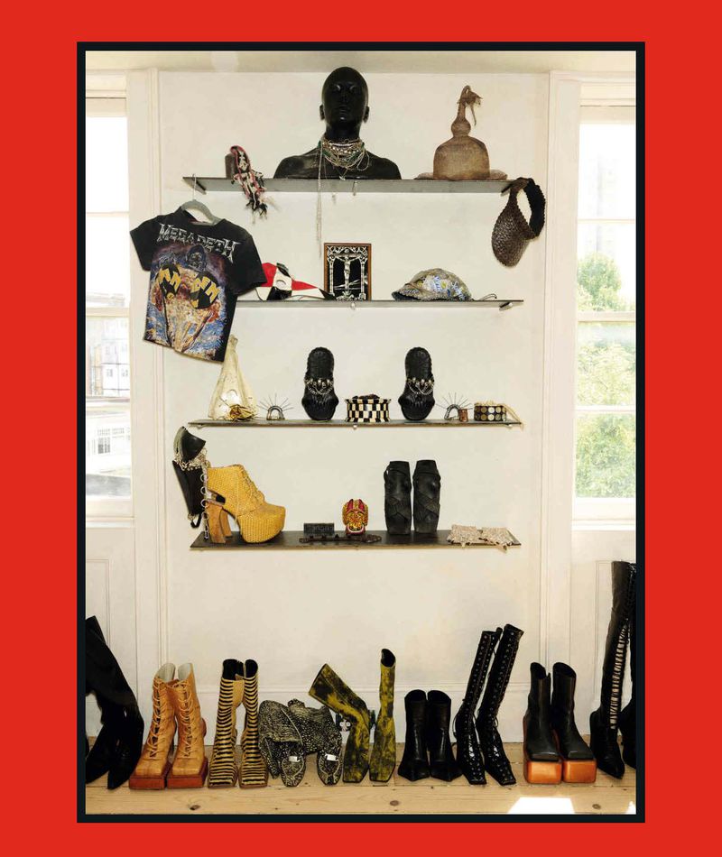 Shelves and floor displaying an eclectic collection of designer boots, platform heels, jewelry, a band shirt, and a mannequin bust.