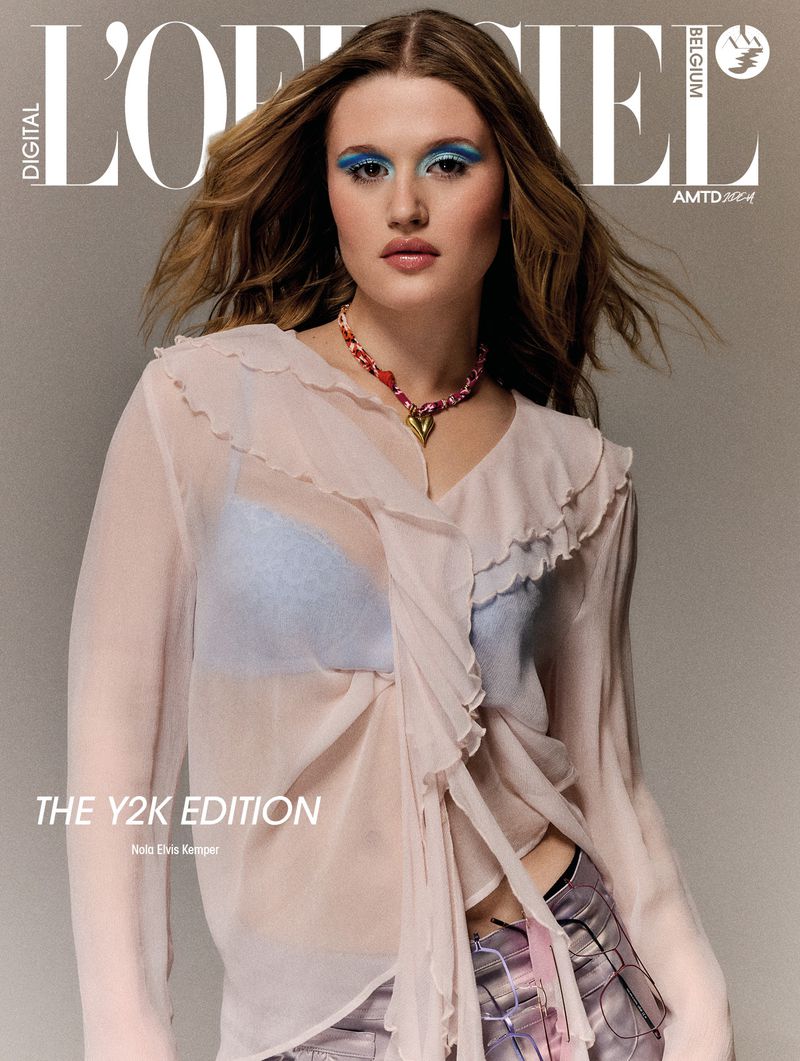 Digital magazine cover featuring a woman with blue eyeshadow wearing a sheer ruffled blouse against a neutral backdrop.