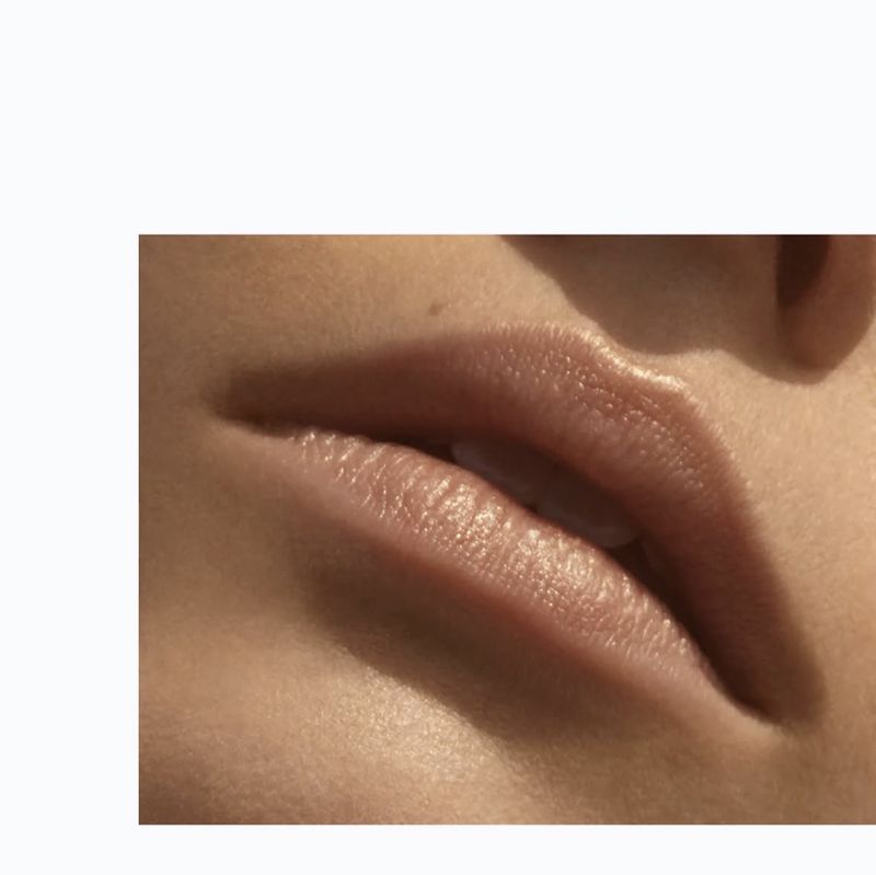 Extreme close-up of model Charlotte Nolting's slightly parted lips with natural nude gloss in soft warm light.