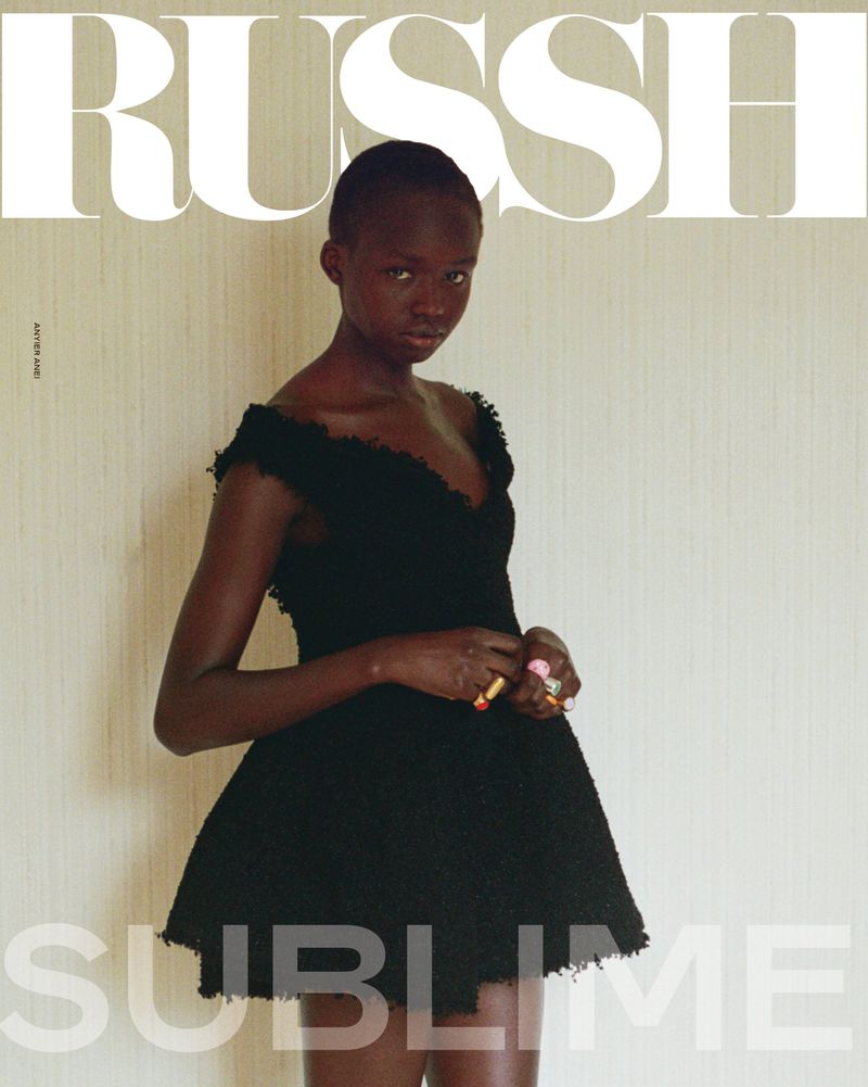 Model Anyier Anei wearing a black textured dress against a pale neutral wall for a Russh fashion magazine cover.