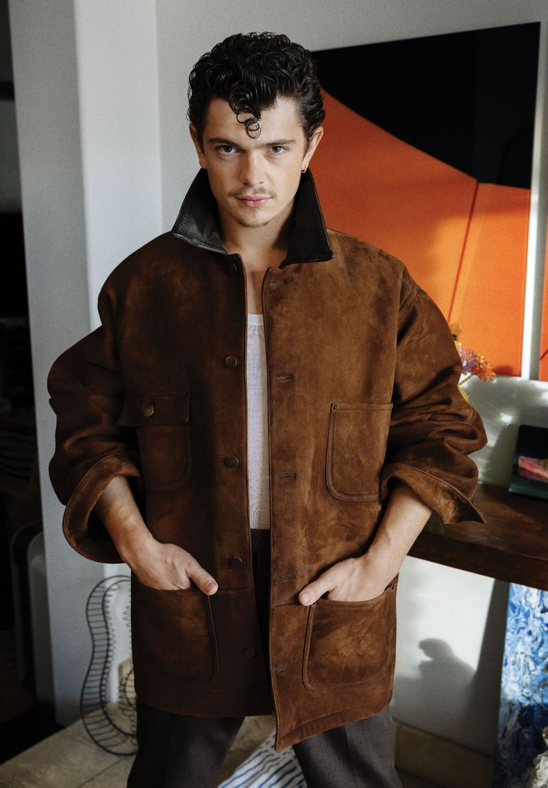 Actor Noah Jupe posing in an oversized brown suede jacket with hands in pockets for Flaunt magazine.
