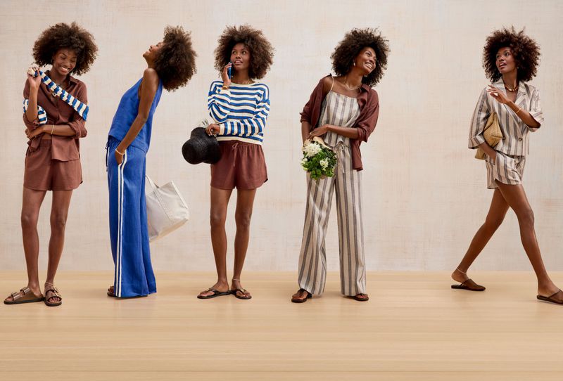 Model with curly afro hair in five different casual summer outfits posed in a row across a neutral studio space.