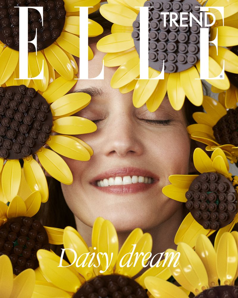 Close-up portrait of a smiling woman surrounded by yellow and brown LEGO brick sunflowers for Elle Hungary