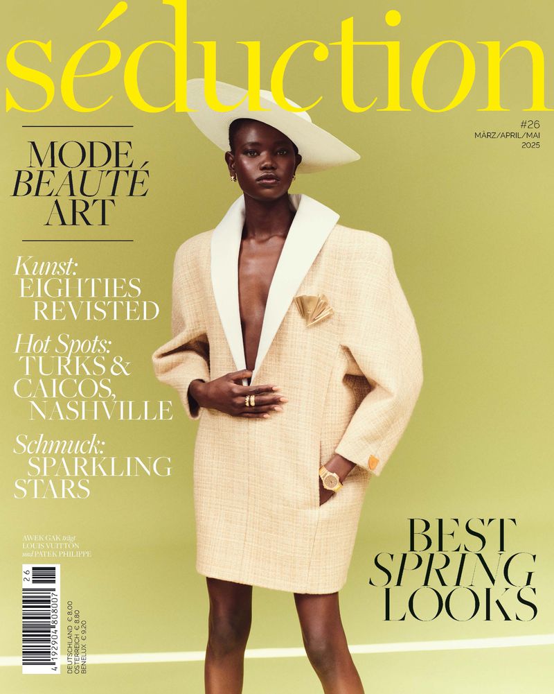 Fashion magazine cover featuring a Black model in a cream-colored oversized blazer and white hat against a light green background.