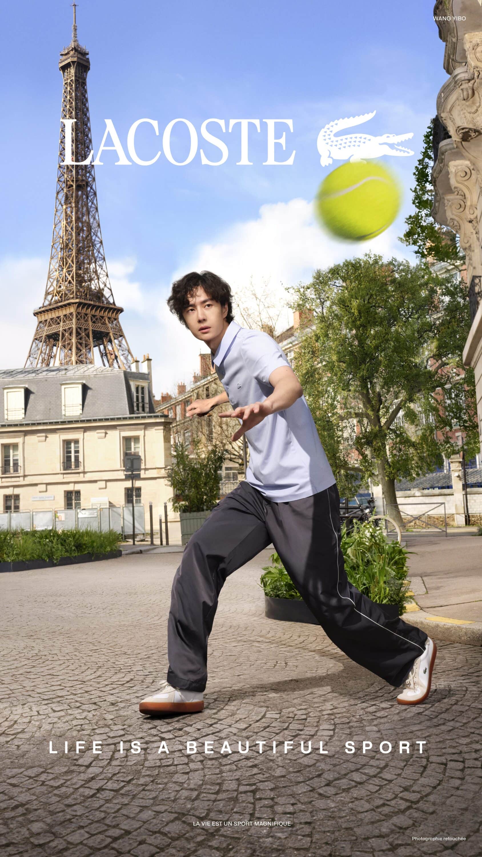 East Asian man in a light blue polo shirt and dark track pants reaching for a tennis ball on a cobblestone Paris street by the Eiffel Tower.