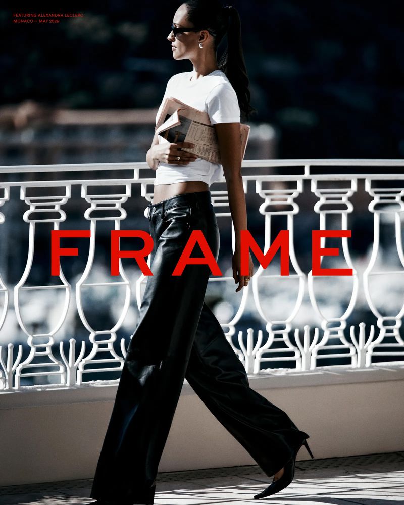 Woman in white t-shirt and black leather pants walking past a white stone balustrade