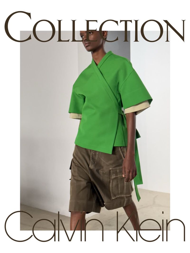 Model wearing a bright green wrap top and brown cargo shorts against a minimalist studio backdrop for Calvin Klein Collection.