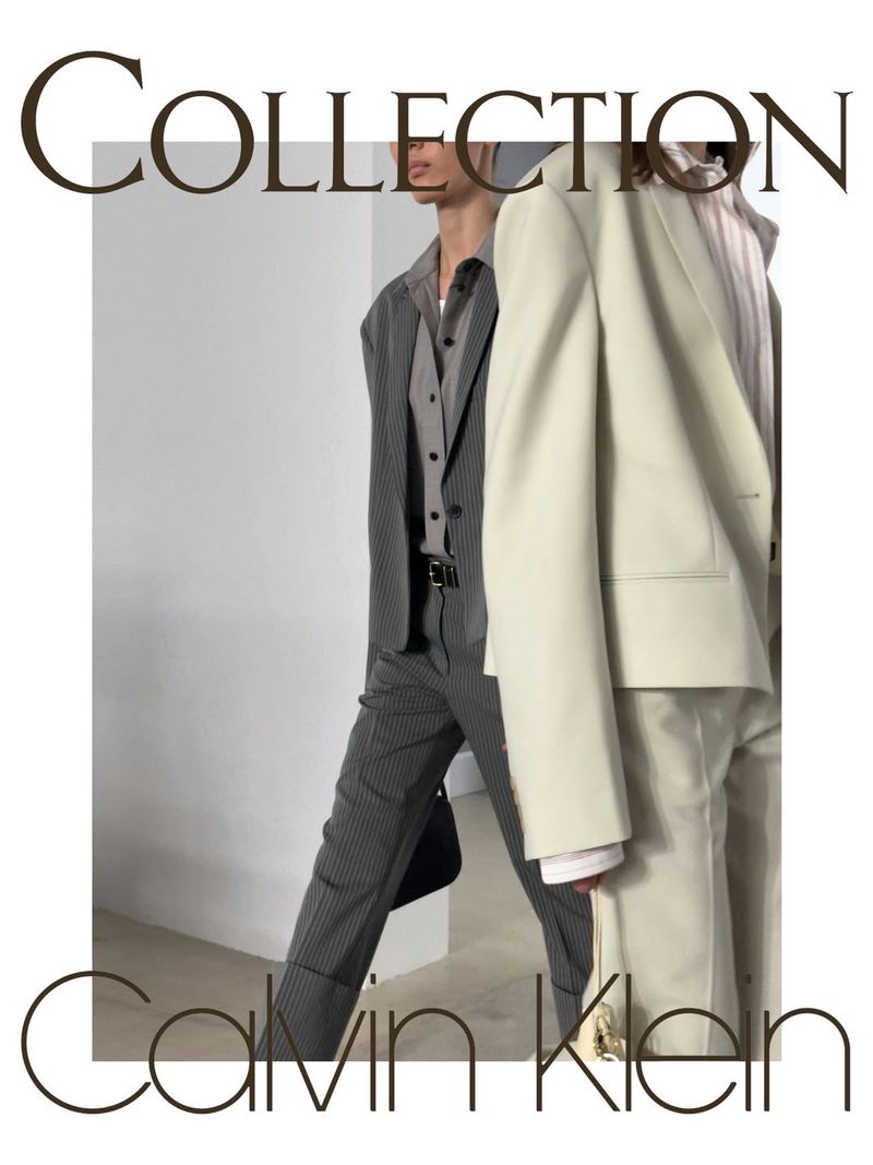 Models in tailored cream and pinstripe suits walking against a white studio background for Calvin Klein.