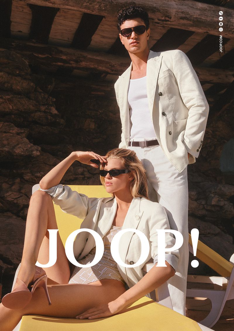 Kim Riekenberg reclining in an off-white blazer and sunglasses next to Gianluca Alessi in a linen suit for Joop!.
