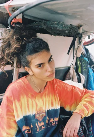 Model Sun Mizrahi wearing an orange and black long-sleeve graphic top in an editorial portrait for Love Want Magazine