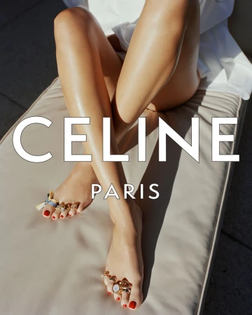 Close-up of bare legs and feet wearing gold toe rings and red nail polish on a sun lounger with Celine Paris text overlay.