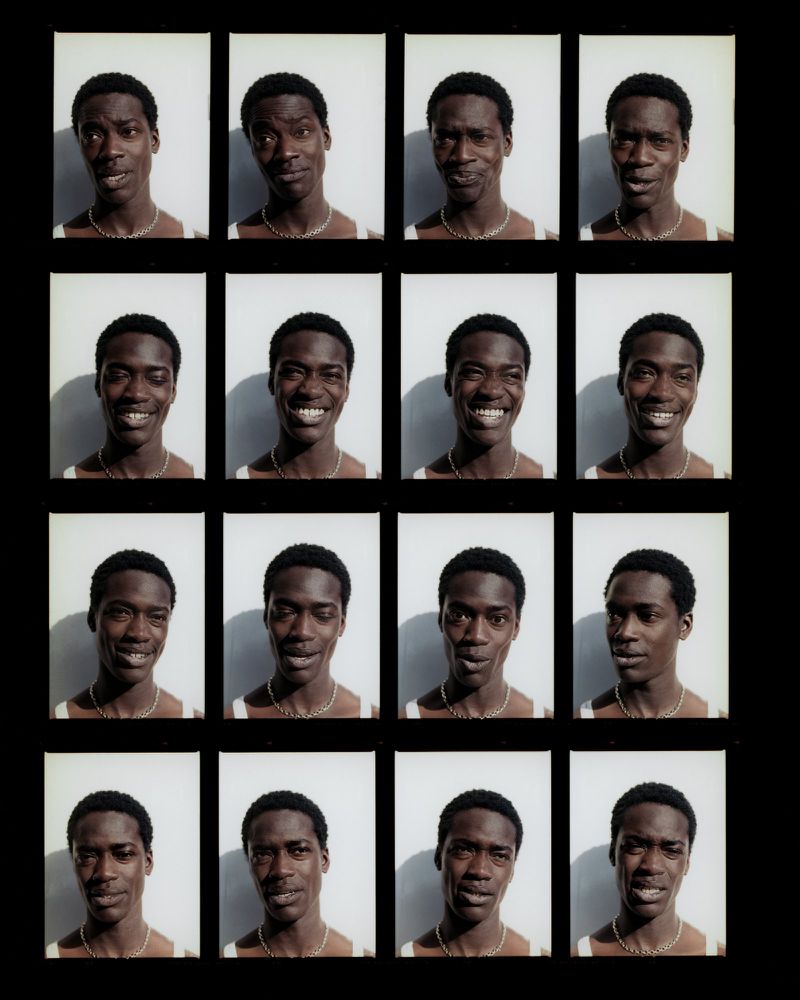 Grid of sixteen portrait photos of a Black man with various expressions, wearing a white tank top and gold chain, against a white background.