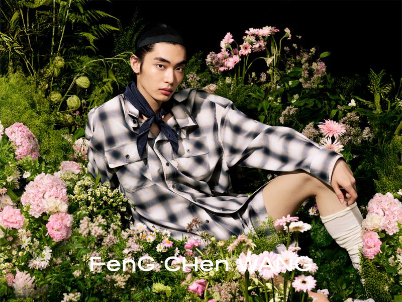 Model reclining amongst lush pink hydrangea blooms and foliage wearing an ombre plaid shirt for Feng Chen Wang.