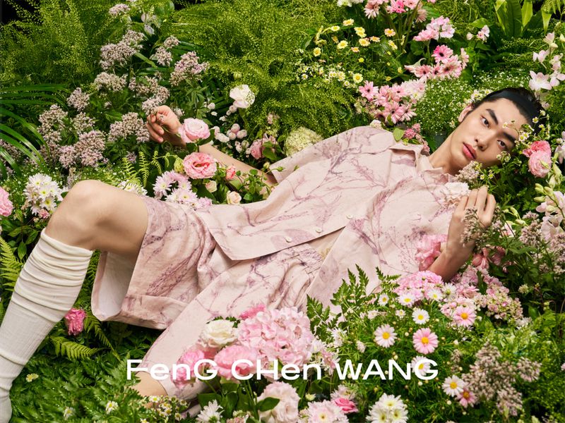 Model reclining among lush pink and white flowers wearing a pale pink patterned shirt and matching shorts set.