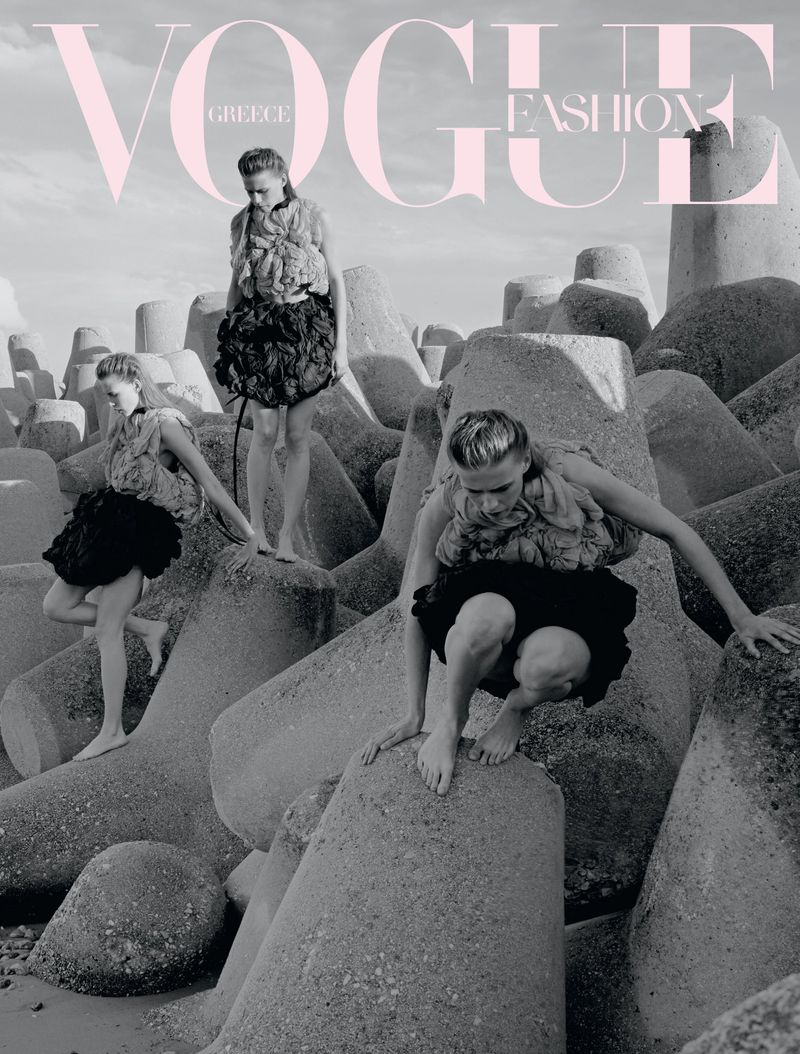 Model Liva Been posed across concrete tetrapods on a coastline for Vogue Greece, wearing a textured top and voluminous black skirt.