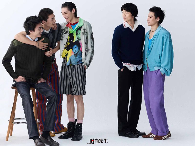 Five young Asian male models posing and interacting in eclectic designer menswear against a plain white studio backdrop.