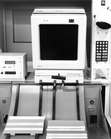 Black and white photograph of a vintage industrial computer terminal with a CRT monitor and mechanical sorting tray.