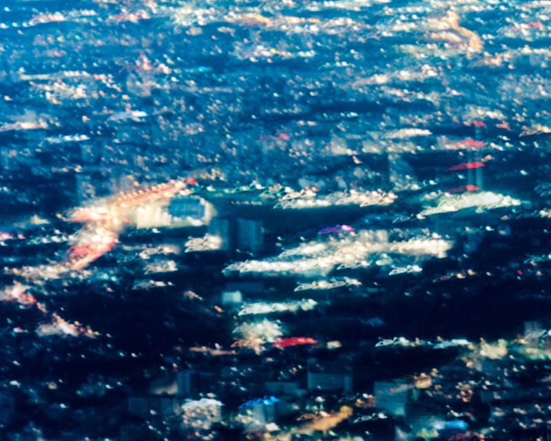 Abstract blurred aerial view of glowing city lights at night in deep blue, white, and amber tones.