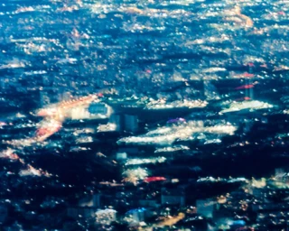 Abstract blurred aerial view of glowing city lights at night in deep blue, white, and amber tones.