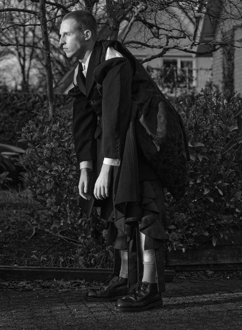 Model Jelle Huizinga posing in a layered, deconstructed black Comme des Garçons suit outdoors in black and white.
