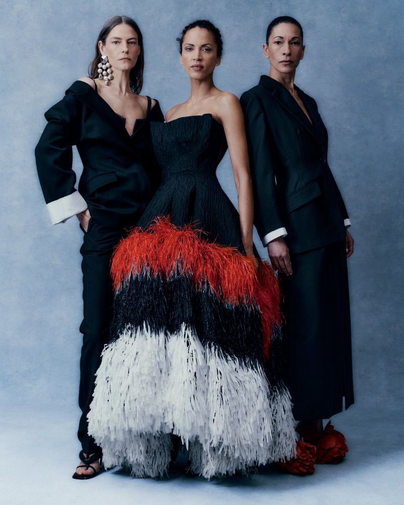 Three models wearing black and feathered dresses posing against a textured blue backdrop for Telegraph Magazine editorial