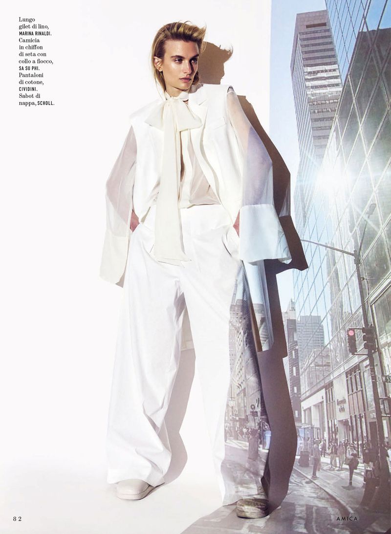 Model Veronika Vilim posing in a wide-leg white trouser suit and sheer pussy-bow blouse for an Amica magazine fashion editorial.