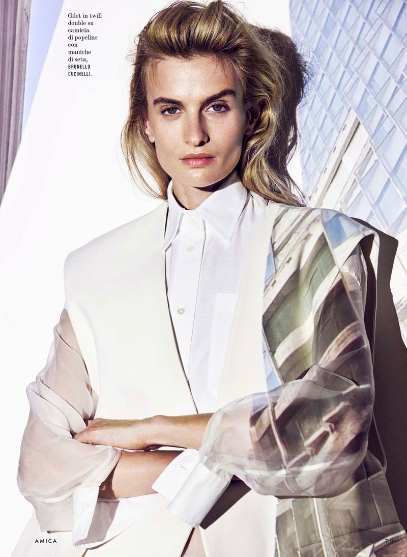 Model Veronika Vilim wearing a white tailored vest and sheer printed sleeves against a modern architectural background.