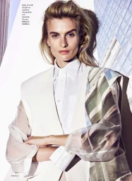 Model Veronika Vilim wearing a white tailored vest and sheer printed sleeves against a modern architectural background.