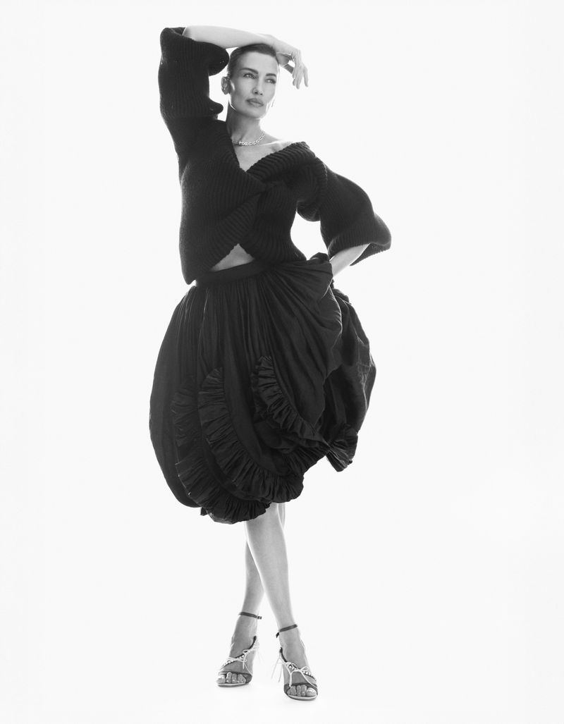 Model Nieves Alvarez poses in an all-black ensemble featuring a cropped sweater and voluminous ruffled skirt against a white backdrop.