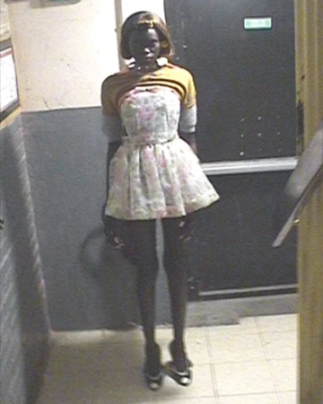 Fashion model in a floral mini dress and heels captured from a high angle security camera perspective in a hallway.