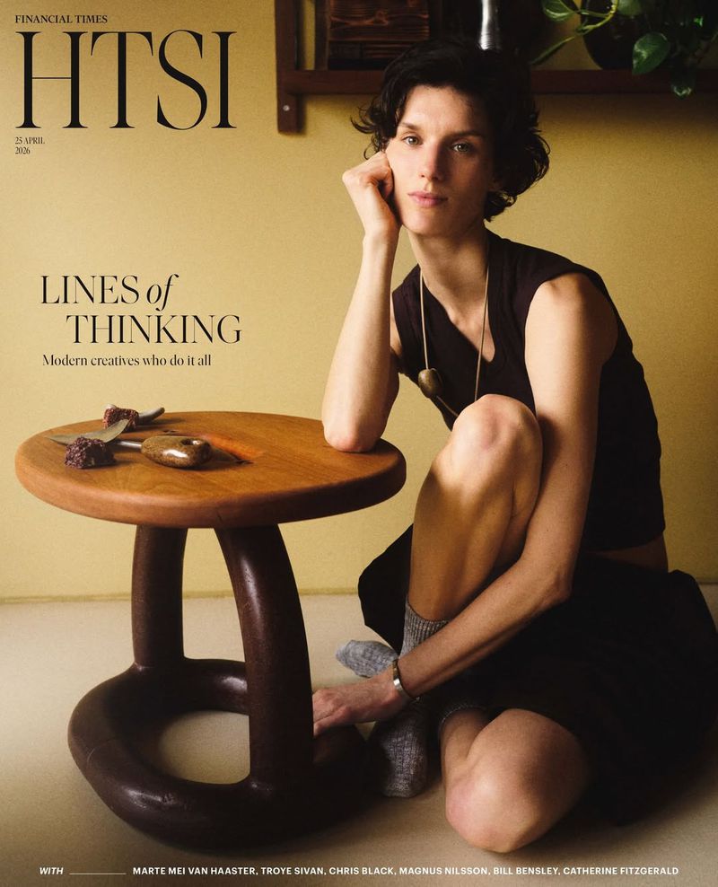 Model Marte Mei van Haaster seated on the floor beside a wooden stool on the cover of Financial Times HTSI Magazine.