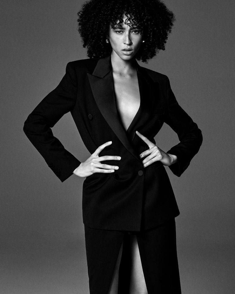 Model Lando van der Schee posing in a black tailored blazer with satin lapels against a seamless dark studio backdrop.