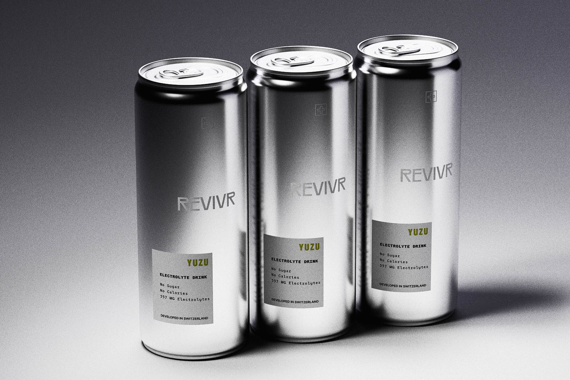 Three silver aluminum cans of REVIVR Yuzu electrolyte drink arranged on a smooth grey gradient studio backdrop.