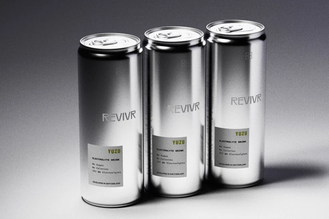 Three silver aluminum cans of REVIVR Yuzu electrolyte drink arranged on a smooth grey gradient studio backdrop.