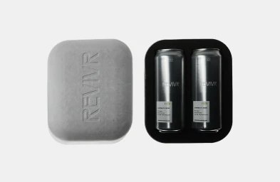REVIVR electrolyte drink packaging with two silver cans in a black tray beside an embossed grey molded case against a white background.