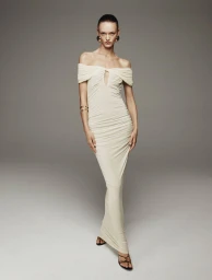 Model wearing a cream off-the-shoulder maxi dress against a grey studio backdrop for My BestFriends Spring Summer 2025.