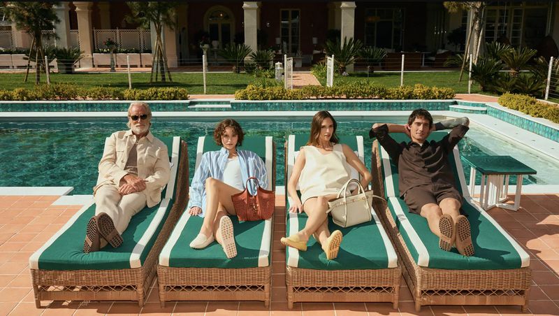 Four models relaxing on lounge chairs by a swimming pool for the Tod's Vacanze Italiane summer campaign.