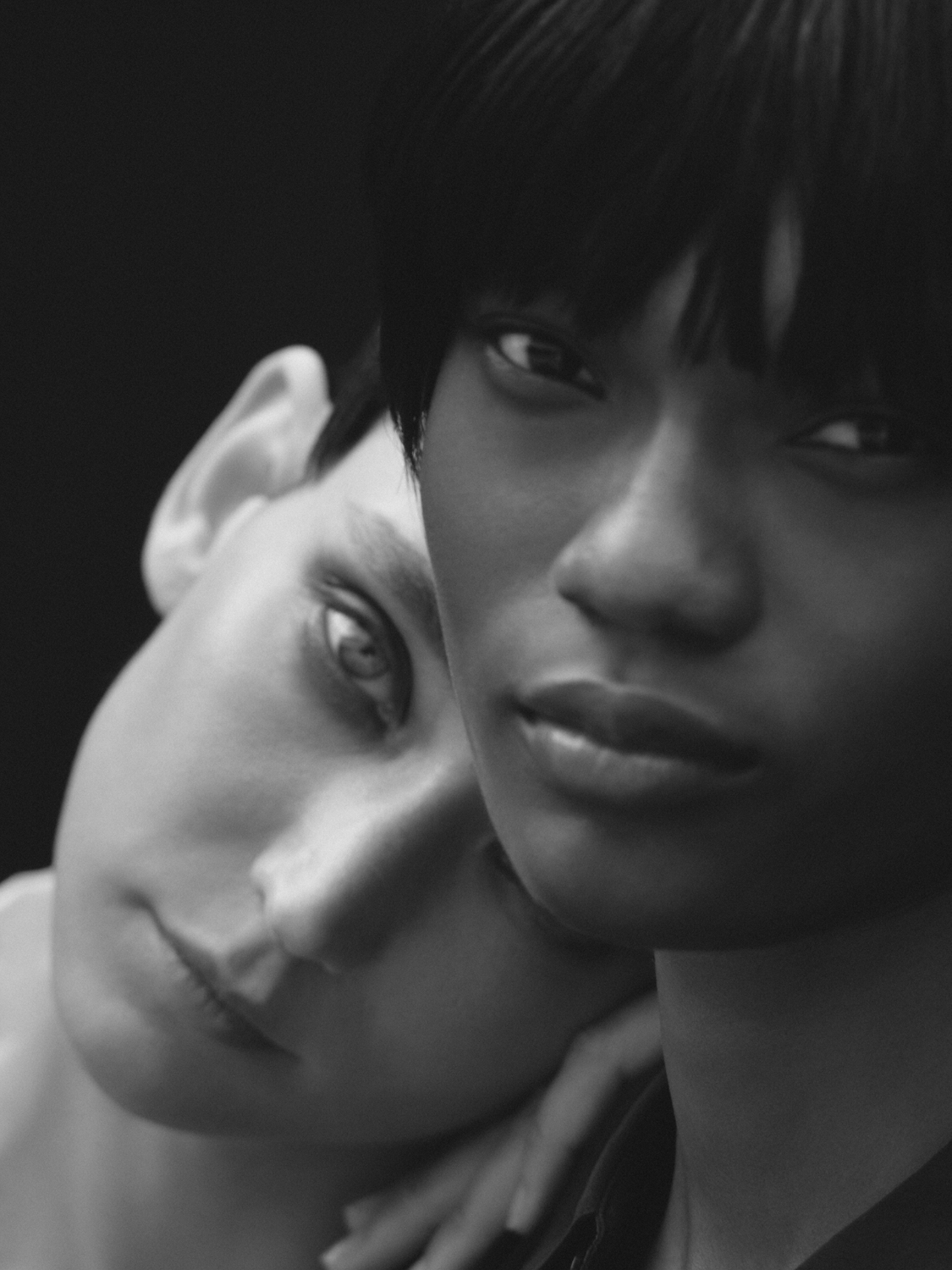 Close-up of two women with contrasting skin tones in a black and white portrait, one with short dark hair, the other with light skin.