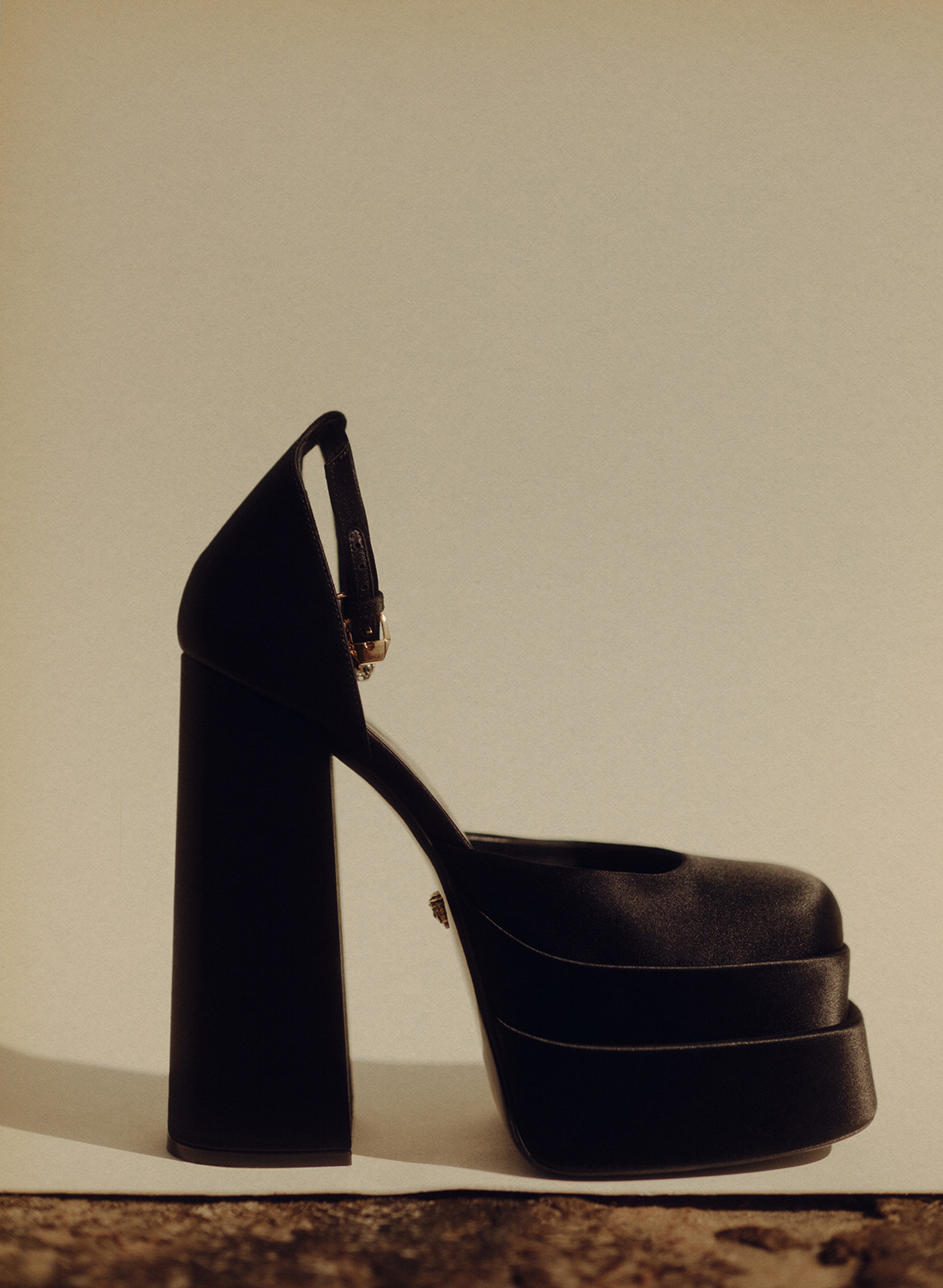 Studio shot of a black platform heel with ankle strap on a neutral background, showcasing its structure, material, and overall fashion appeal.