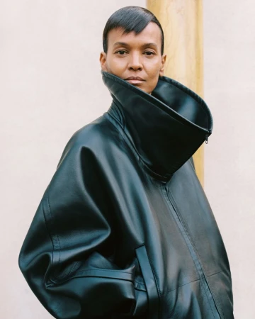 Model Liya Kebede wearing an oversized black leather jacket with an exaggerated funnel collar against a neutral background.