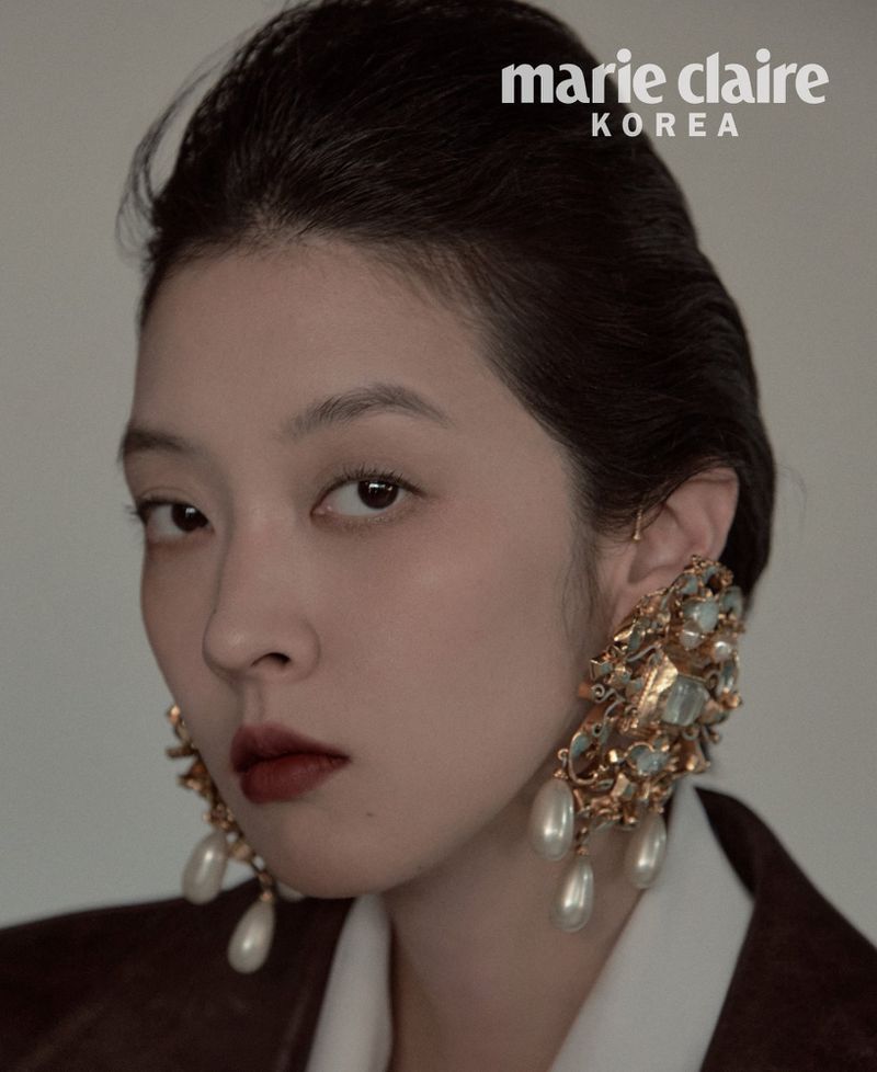 Model So Young Kang wearing ornate gold and pearl chandelier earrings and a dark blazer for Marie Claire Korea.