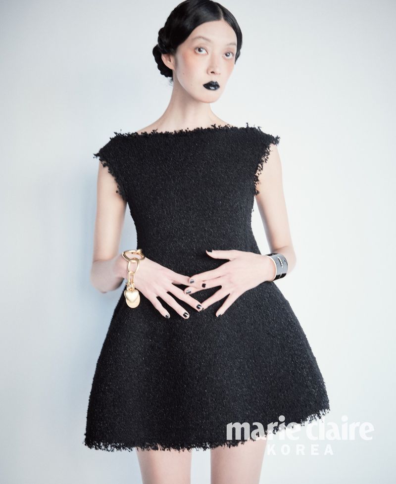 Model So Young Kang wearing a black mini dress with dark lipstick and metallic accessories against a white background for Marie Claire Korea.