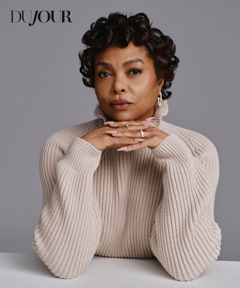 Actor Taraji P. Henson in a beige ribbed knit turtleneck sweater with hands under her chin against a grey studio backdrop.