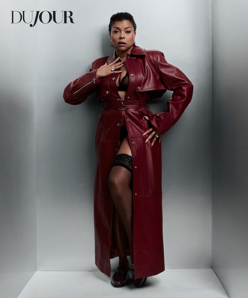 Taraji P. Henson posing in an open burgundy leather trench coat and black lingerie against a silver backdrop.