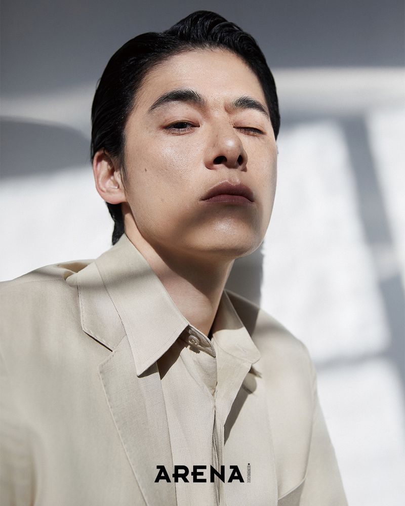 Model Kim Won wearing a beige blazer and collared shirt in direct sunlight with cast shadows for Arena Homme+ Korea.