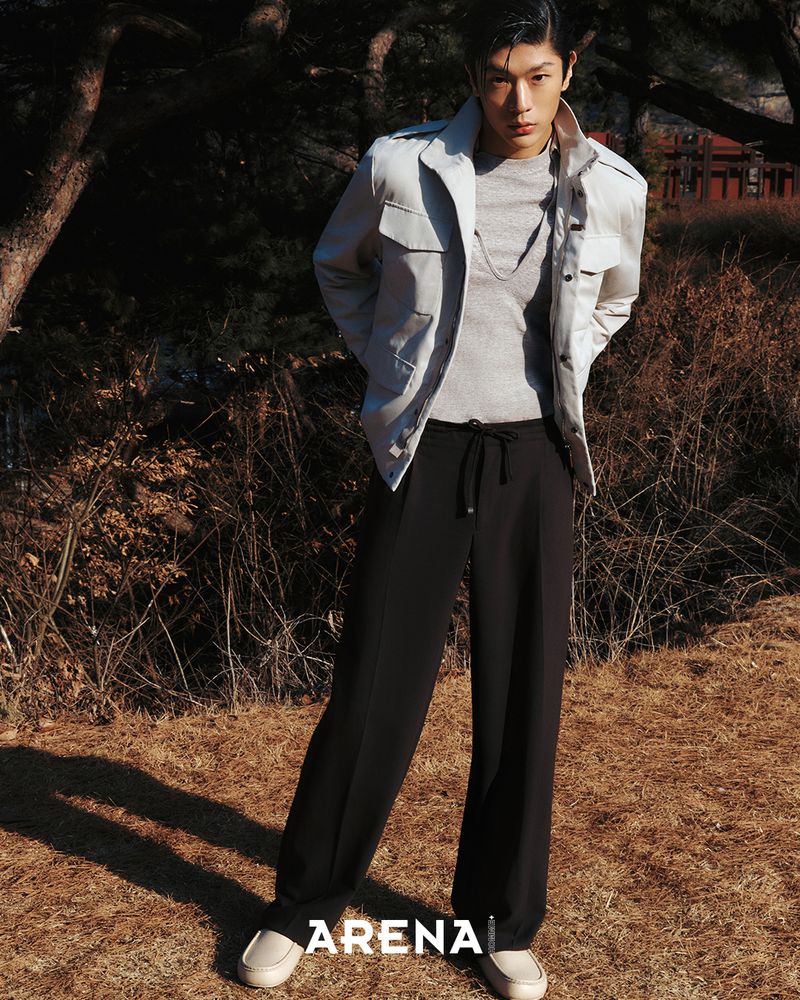 Model Woohyeong Jang posing outdoors in a light field jacket, black wide-leg trousers, and cream leather loafers.