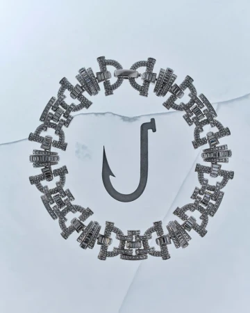 A sparkling diamond chain bracelet encircles a dark metallic fishing hook resting on a pale blue cracked ice surface.